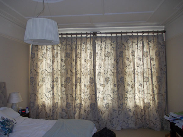 Wall to wall wooden pole with interlined pinch pleat curtains covering the window