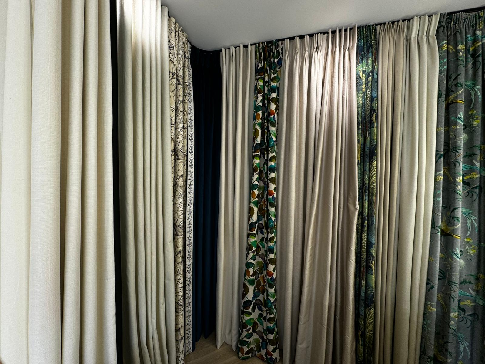 A display of curtains in our North London showroom using various fabrics with a selection of curtain headings - Pinch Pleat, Cartridge Pleat, Wave Heading, Inverted Pleat, Pencil Pleat and more